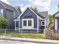 Charming blue home featuring a well-maintained front yard and decorative American flags along the picket fence at 1613 E Ohio St, Indianapolis, IN 46201