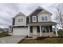 Two-story home features a two car garage, dark brown siding and cream colored accents under a cloudy sky at 17039 Silo Ridge Way, Noblesville, IN 46060