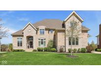 Elegant two-story home featuring stone and brick facade, arched entryway, and professionally landscaped lawn at 3384 Homestretch Dr, Carmel, IN 46032