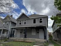 Two-story duplex with gray siding, broken windows, and a shared front porch, needs renovation at 433 Jefferson Ave, Indianapolis, IN 46201