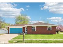 Charming red brick home featuring a blue garage door and manicured lawn under a blue sky at 4905 Candy Spots Dr, Indianapolis, IN 46237