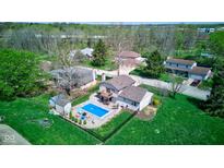Aerial view of home showcasing the backyard pool, patio, deck, and well-manicured lawn in a verdant neighborhood at 4977 Beechwood Rd, Avon, IN 46123