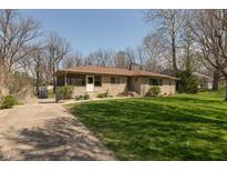 Charming single-story home with a stone facade, mature trees, and a well-maintained lawn at 614 Debra Ln, Indianapolis, IN 46217