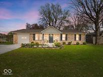 Charming brick ranch home features a well-manicured lawn, attached garage, and inviting front porch with seating at 390 Lakeview Dr, Noblesville, IN 46060
