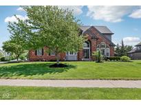 Charming brick home featuring a landscaped yard and mature tree, showcasing curb appeal at 7323 Elm Ridge Dr, Indianapolis, IN 46236