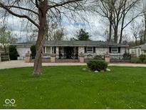 Charming brick ranch-style home with well-maintained lawn and decorative fence, creating a welcoming curb appeal at 7334 E 14Th St, Indianapolis, IN 46219