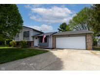 Charming home featuring a two-car garage, well-manicured lawn and patriotic American flag at 8232 N Chaucer Ct, Columbus, IN 47201
