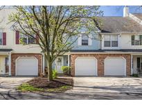 Townhouse with a brick facade, white garage door, and a well-manicured front yard with a young tree at 9575 Thradd St, Fishers, IN 46038