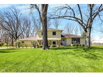 Charming two-story home with yellow siding, landscaped yard, and mature trees at 11006 Timber Ln, Carmel, IN 46032
