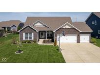 Charming brick home featuring an attached two-car garage and a well-manicured lawn, providing great curb appeal at 15142 Blue Ribbon Blvd, Fishers, IN 46040