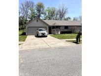 Charming single-story home features a gray brick exterior, well-maintained lawn and a long driveway at 4211 Medina Way, Indianapolis, IN 46227