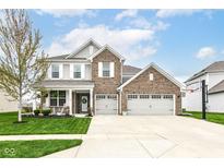 Charming two-story brick home featuring a three-car garage, well-manicured lawn, and inviting front porch at 6040 Juniper Ct, Whitestown, IN 46075