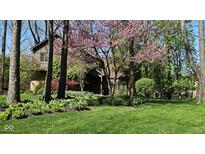 Charming home exterior featuring a lush green lawn, mature trees, and flowering bushes at 889 Cedar Wood Pl, Carmel, IN 46032