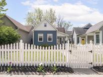 Charming home features a blue exterior, white picket fence, and well-manicured lawn, enhancing its curb appeal at 1429 Fletcher Ave, Indianapolis, IN 46203