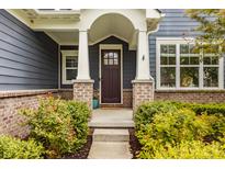 Charming front entrance with brick accents, a covered porch, and a well-maintained garden landscape at 2785 W High Grove Cir, Zionsville, IN 46077