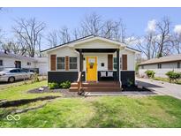 Charming home featuring a bright yellow door, inviting front porch, and fresh landscaping at 3134 Orchard Ave, Indianapolis, IN 46218