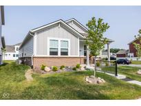 Charming single-story home with a brick foundation, a well-manicured lawn, and a cozy front porch at 360 Lincoln W Cir, Fortville, IN 46040