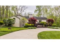 Charming stone home featuring lush landscaping, a curved driveway, and a spacious front deck for outdoor enjoyment at 8901 Shetland Ln, Indianapolis, IN 46278