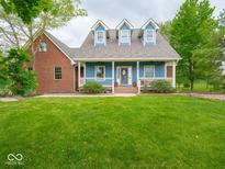 Charming blue home boasts a welcoming front porch, manicured lawn, and classic architectural details for curb appeal at 9243 Compton Farm Ln, Indianapolis, IN 46259