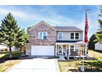 Charming two-story home featuring brick accents, a covered porch, and a well-manicured front yard at 12981 Coyote Run, Fishers, IN 46038