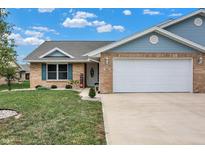 Charming brick home featuring a well-manicured lawn and a two-car attached garage at 400 E Charter Dr, Muncie, IN 47303