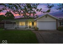 Charming home featuring a well-manicured lawn, inviting porch, and two-car garage at twilight at 1002 Prairie Depot, Indianapolis, IN 46241
