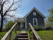 Charming home with gray siding, white trim, front porch, and concrete steps leading to the front door at 2819 W 16Th St, Indianapolis, IN 46222
