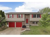 Charming home with red shutters, an attached garage, and a brick facade around the entryway at 5335 Honey Comb Ln, Indianapolis, IN 46221