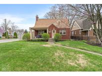Charming brick home featuring a well-maintained lawn and inviting front porch at 5697 Broadway St, Indianapolis, IN 46220