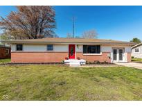 Charming ranch-style home boasts a brick facade, bright red door, and beautifully manicured front yard at 598 Collier St, Columbus, IN 47201