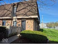 Exterior view of a brick townhouse featuring a small yard, tidy landscaping, and a well-maintained facade at 7368 Country Brook Dr # 7368, Indianapolis, IN 46260