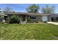 Charming brick ranch-style home with attached garage, lush lawn, and beautiful landscaping at 1021 N Bolton Ave, Indianapolis, IN 46219