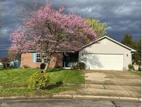 Charming home with a lush green lawn and beautiful flowering tree in the front yard at 1102 Branifield Ct, Franklin, IN 46131