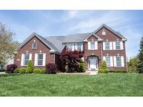 Beautiful two-story brick home with a manicured lawn and lush landscaping at 11592 Saltford Ln, Fishers, IN 46037