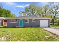 Charming one-story home featuring a gray brick exterior, a blue front door, and an attached garage at 1243 N Post Rd, Indianapolis, IN 46219
