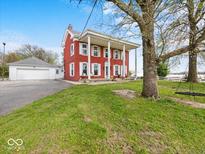 Exterior view of the residence showcasing the classic red brick, white columns, and spacious front yard at 1394 N Michigan Rd, Shelbyville, IN 46176