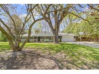 Ranch-style home with stone and painted brick, mature trees, well-maintained lawn, and attached two car garage at 2325 Melody Ln, Anderson, IN 46012