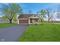 Charming home featuring an attached garage, a well-manicured lawn and a paved driveway on a sunny day at 4525 Shelbyville Rd, Indianapolis, IN 46237