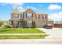A charming two-story home boasts a well-manicured lawn, brick facade, and a spacious three-car garage at 6725 Tramcus Dr, Indianapolis, IN 46260