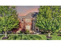 Attractive brick home with a well-manicured lawn and mature trees under a colorful sky at 11341 Abercairn Ct, Zionsville, IN 46077