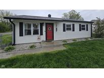Charming single-story home with a red front door, black shutters, and manicured landscaping at 2650 Woodrow Ave, Indianapolis, IN 46241