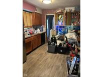 Features a sink, oven, wooden cabinetry, and laminated floors, but is cluttered and in need of decluttering at 3742 S Walcott St, Indianapolis, IN 46227