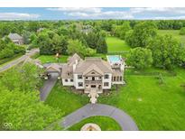 Expansive estate featuring a pool, lush landscaping, circular driveway, and a charming two-story residence at 6990 Old Hunt Club Rd, Zionsville, IN 46077