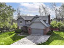 Charming gray home featuring an attached garage, manicured lawn, and mature trees in a peaceful setting at 8242 Windhaven Cir, Indianapolis, IN 46236