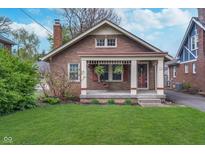 Charming brick bungalow featuring a cozy front porch with a swing and a well-manicured lawn at 914 Kessler Blvd E Dr, Indianapolis, IN 46220
