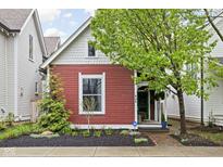Charming red two-story home featuring manicured landscaping, mature tree and covered front entry at 946 Stillwell St, Indianapolis, IN 46202