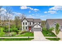 Beautiful two-story home showcases a well-kept lawn and inviting gray facade with a contrasting orange front door at 10294 Pigato Dr, Zionsville, IN 46077