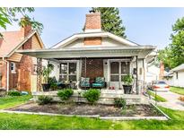 Charming home with an inviting front porch, lovely landscaping, and classic architectural details at 1030 N Butler Ave, Indianapolis, IN 46219