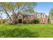 Beautiful brick home with a lush green lawn and mature tree providing shade at 11469 Burkwood Dr, Carmel, IN 46033