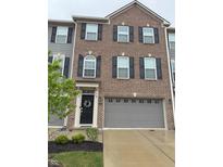 A three-story brick townhouse featuring black shutters, gray siding, and a gray garage door at 17364 Graley Pl, Westfield, IN 46074